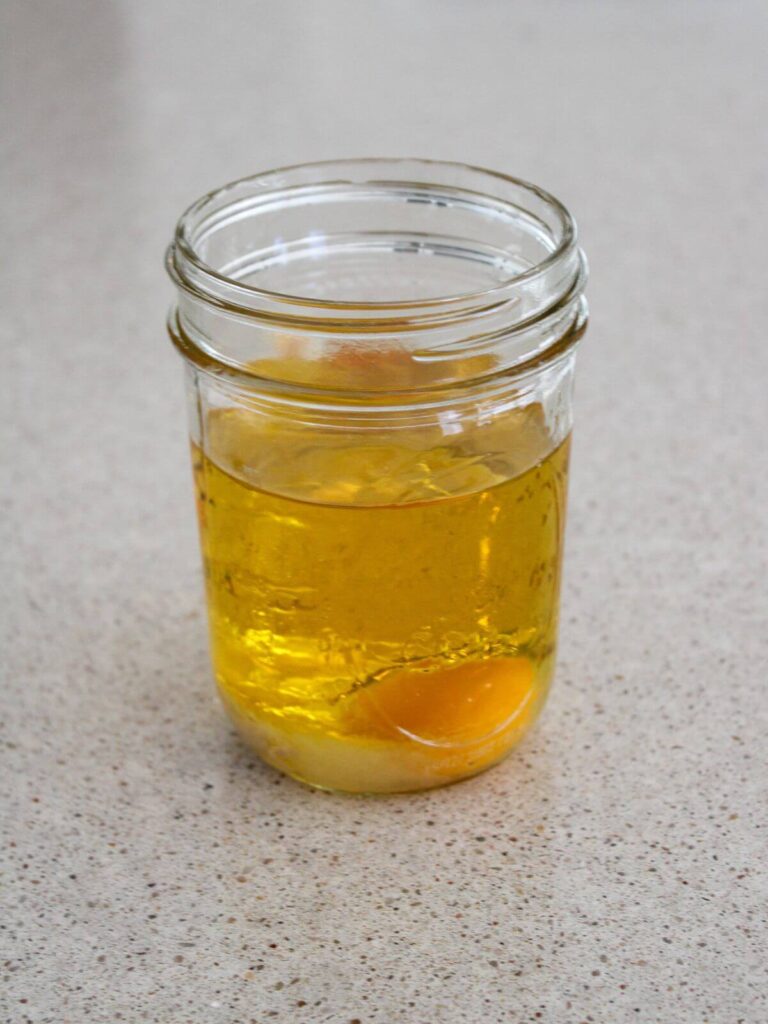 Avocado oil, salt, lemon juice, dijon mustard and egg in a glass mason jar