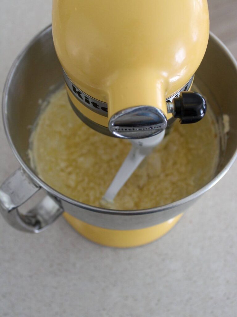 adding eggs and vanilla to the sugar mixture in a kitchen aid bowl 