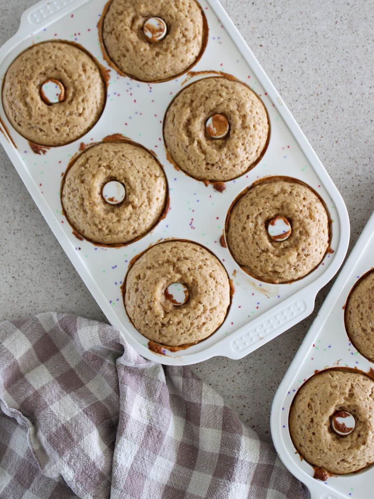 Donuts baked in a silicon donut pan with a plaid napkin next to it
