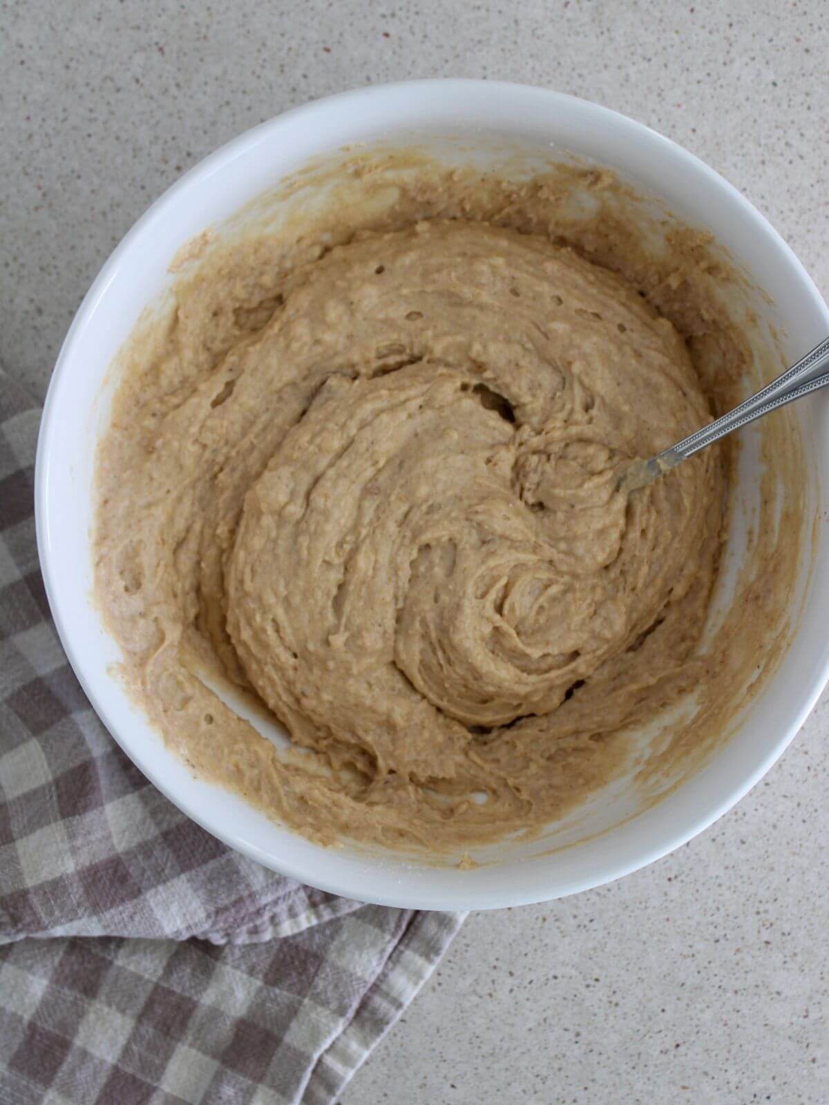 all the ingredients mixed together in a white bowl with a silver spoon and a plaid napkin