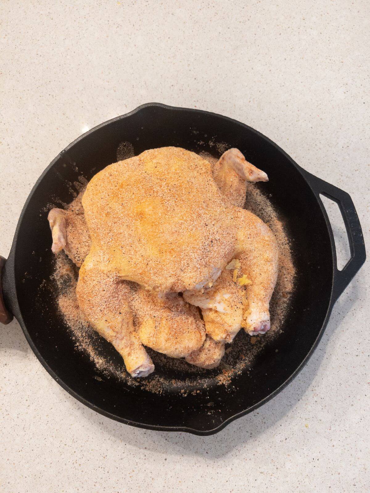 seasoned whole chicken in a cast iron pan