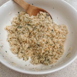 Easy Cheesy Garlic Rice in a White bowl with a wooden spoon