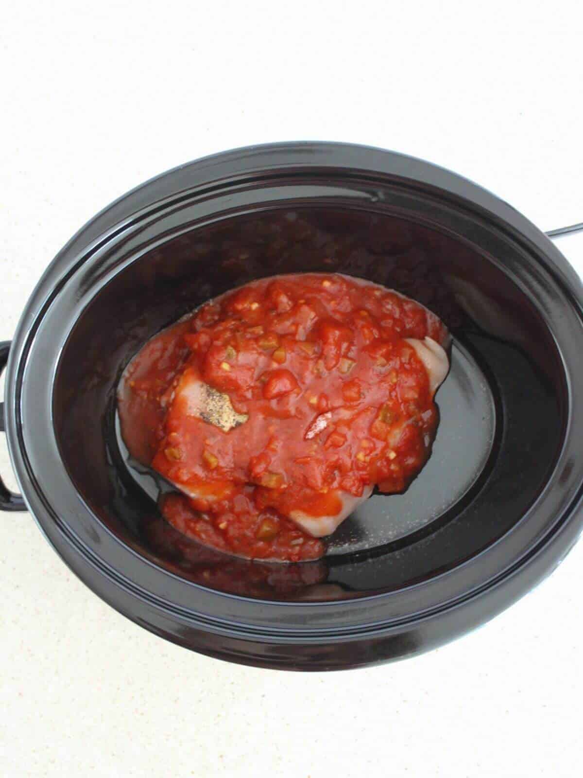 salsa, seasonings and chicken added to a crockpot.