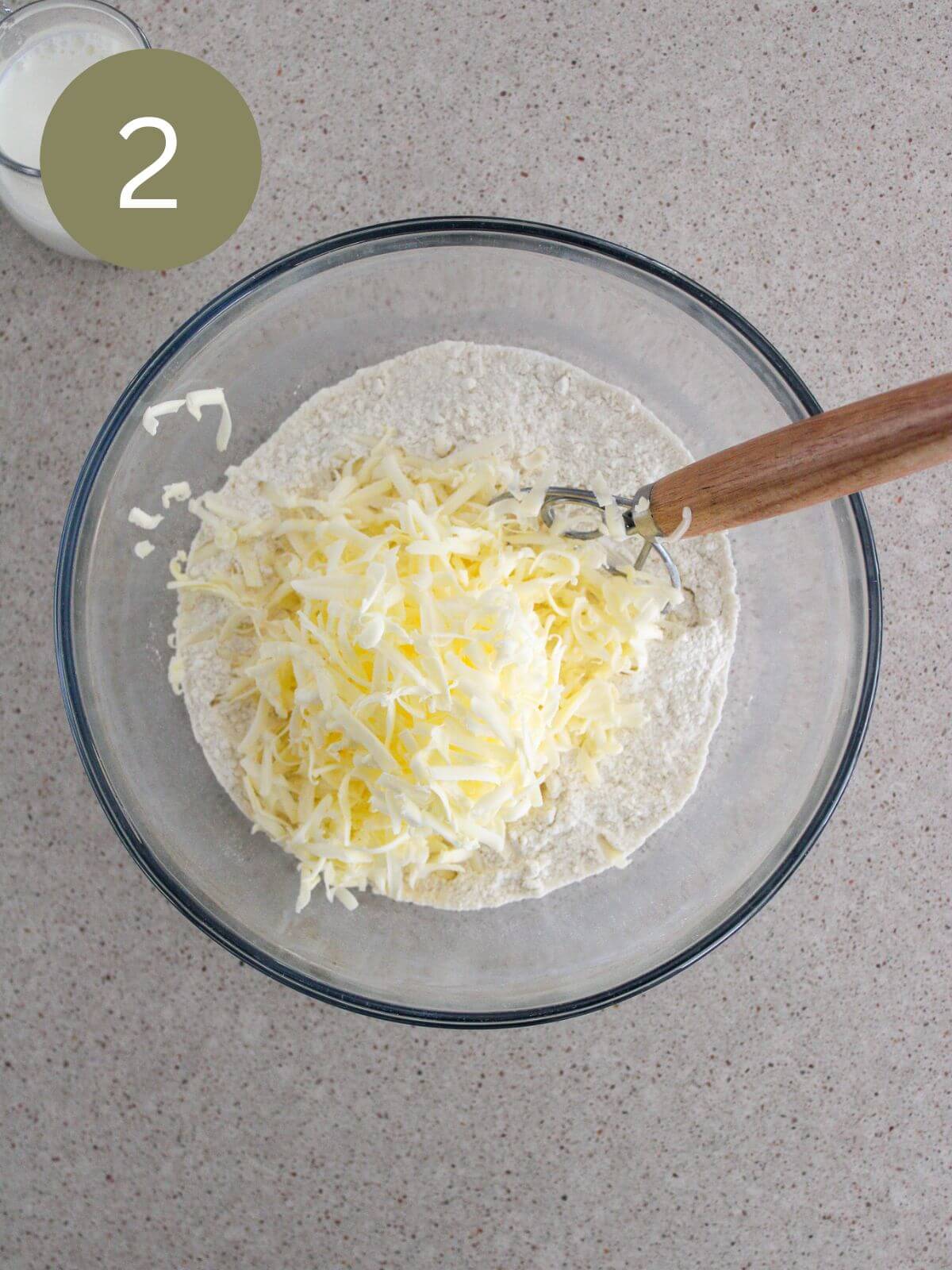 Butter grated into the dry mix in a clear glass bowl with a dough whisk and milk off to the side