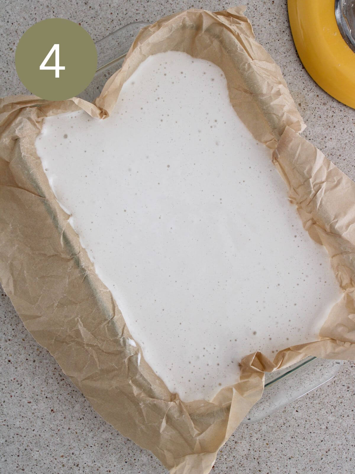 the marshmallows setting in a glass pan with parchment paper
