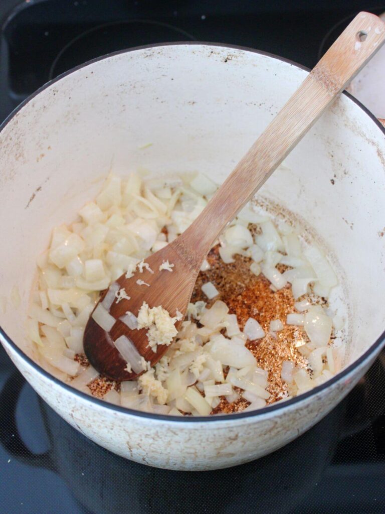 Sautéing the onions and garlic in a dutch oven with a wooden spoon