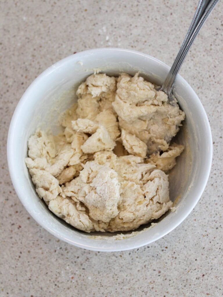Dumpling being formed in a white bowl with a silver spoon
