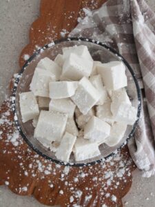 Gut-Healing Marshmallows in a clear bowl on a cutting board with powdered sugar and a plaid napkin