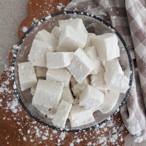 Gut-Healing Marshmallows in a clear bowl on a cutting board with powdered sugar and a plaid napkin