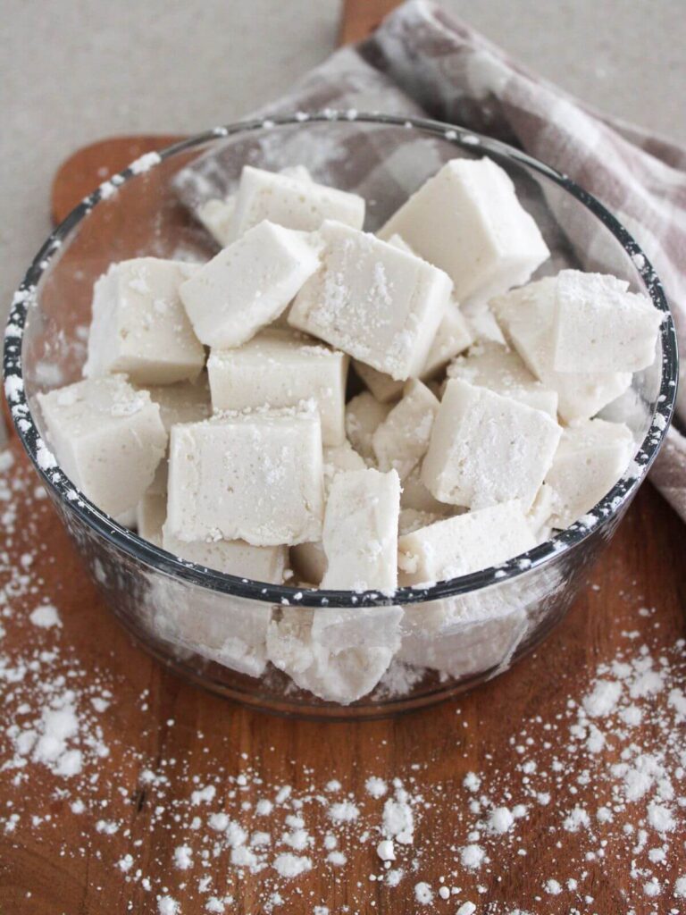 marshmallows in a glass bowl on a cutting board with a plaid napkin