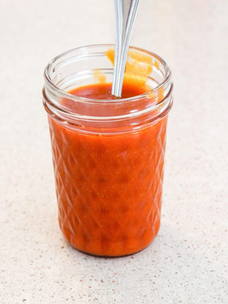 Hot sauce in a small mason jar with a silver spoon ready to eat