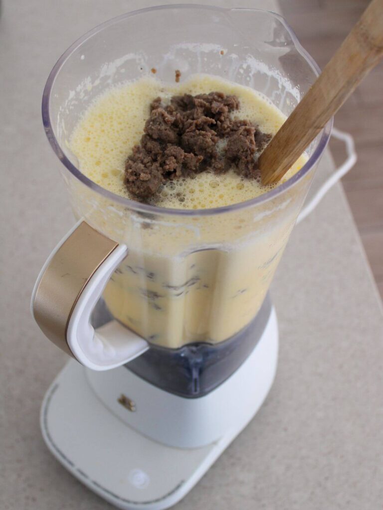 adding the cooked sausage and cheese to the egg mixture in the blender