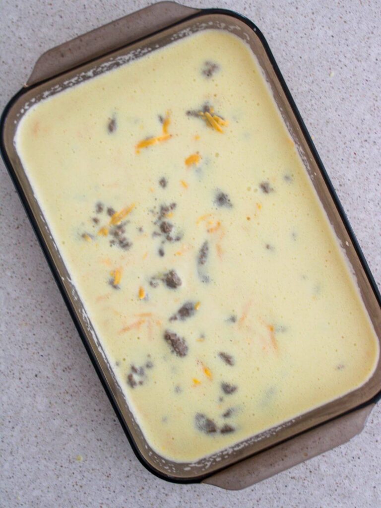 Pouring the sausage and egg mixture into the 9x12 brown glass baking pan
