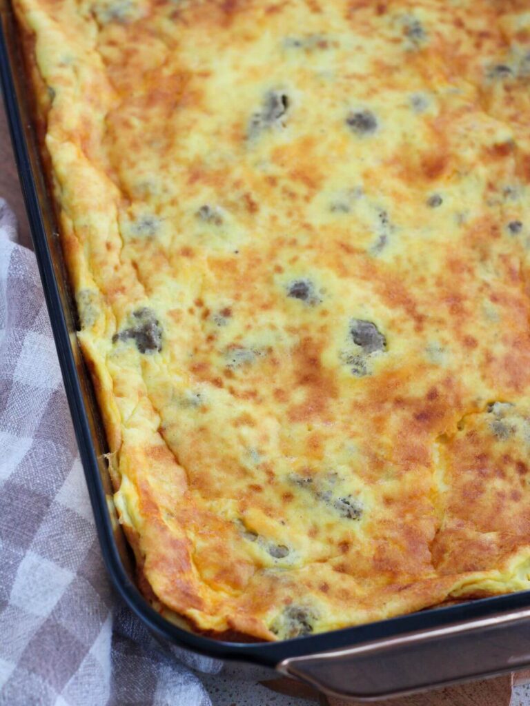 the egg and sausage bake finished in a glass pan on a cutting board with a plaid napkin