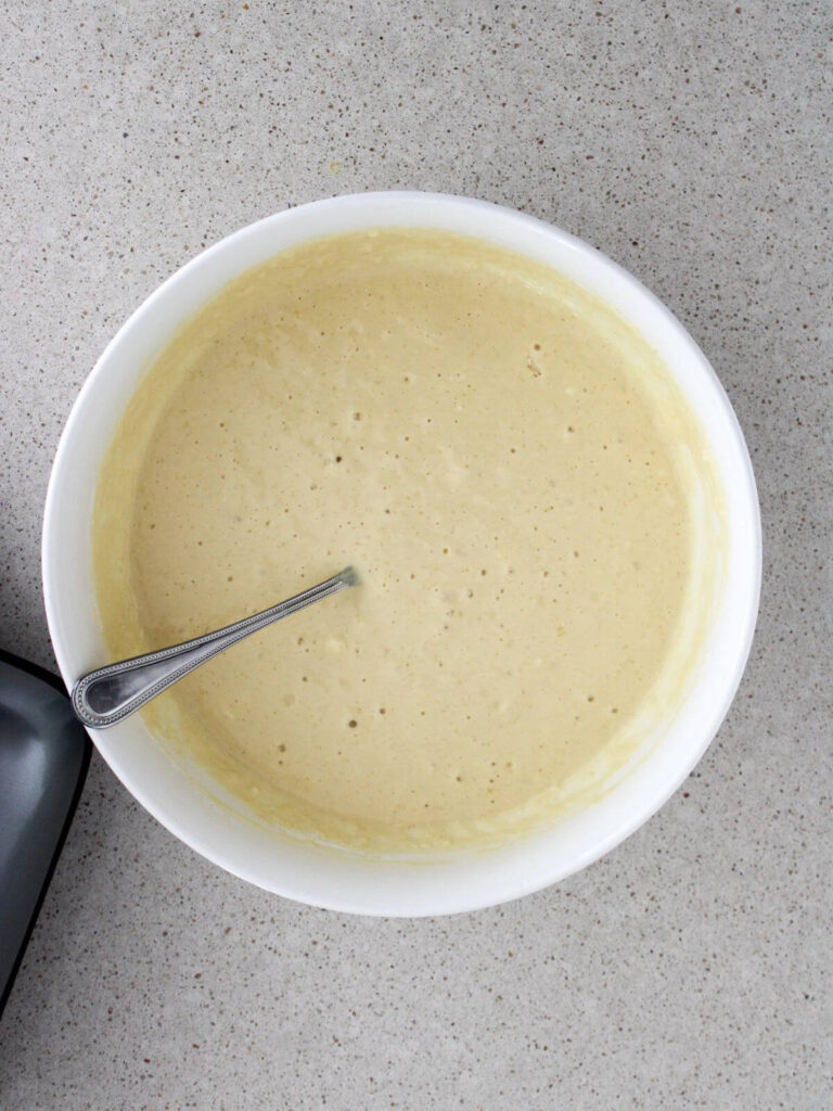 letting the batter rest in a white bowl with a silver spoon