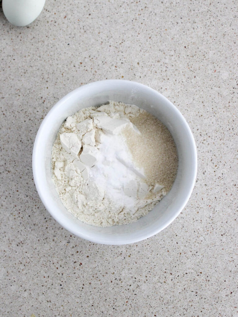Mixing the flour, baking powder, baking soda, and  salt in a small white bowl