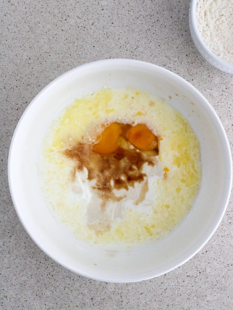 Mixing the eggs, milk, Greek yogurt, butter and vanilla in a white bowl