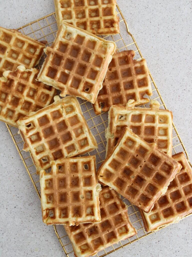 Cooked waffles on a golden cooling rack 