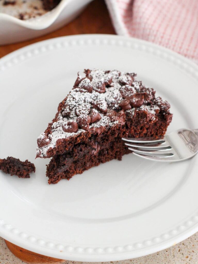a slice of the chocolate cake on a white plate with a silver spoon