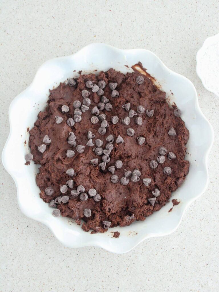Cake ready to bake in a white pie pan topped with extra chocolate chips