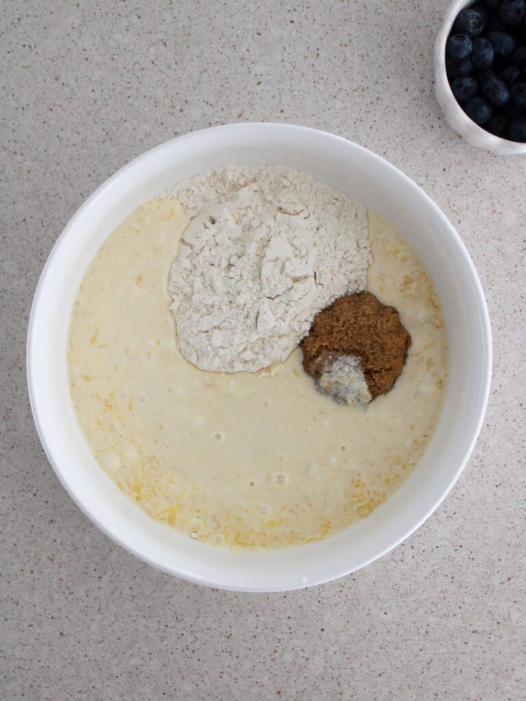 Mixing the wet ingredients with the dry ingredients in a large white bowl