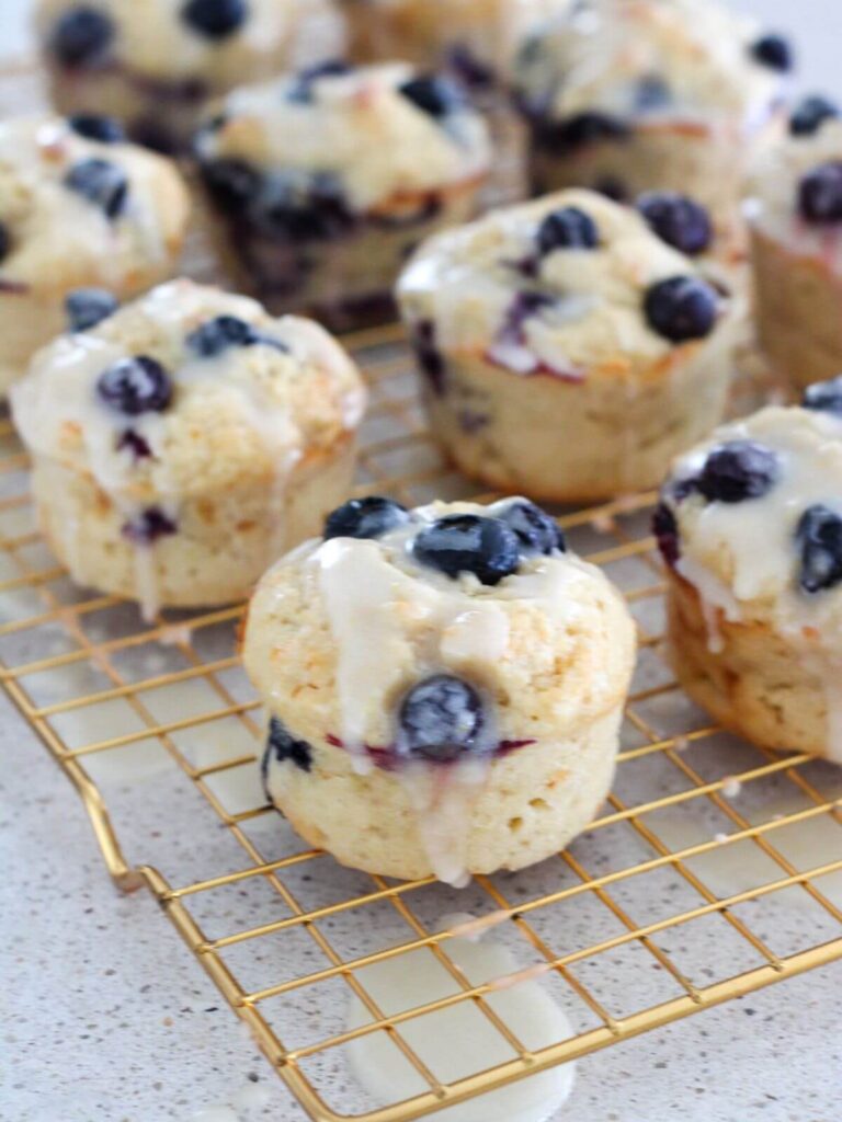 Blueberry Lemon muffins on a golden cooling rack 