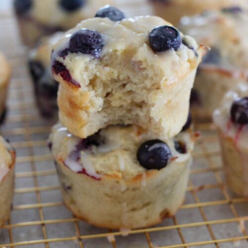 blueberry lemon muffins stacked on top of each other a golden cooling rack