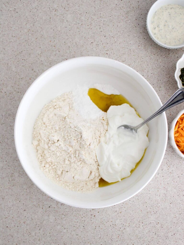 Mixing the ingredients for the dough in a white bowl with a silver spoon. 