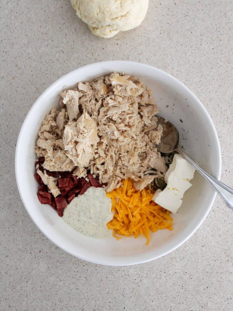 Mixing the ingredients for the filling for the pockets in a white bowl with a silver spoon