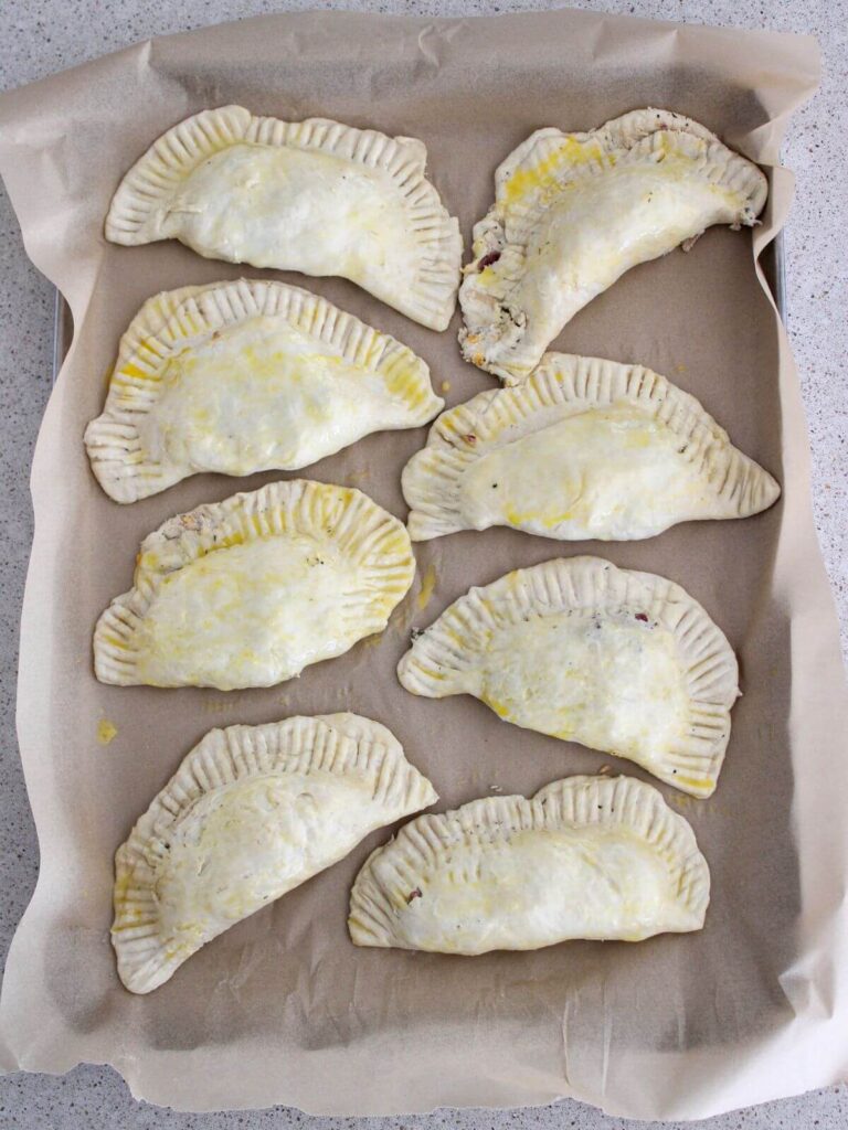 egg washed the tops of the pockets on a parchment lined sheet pan. the pockets ready to bake.
