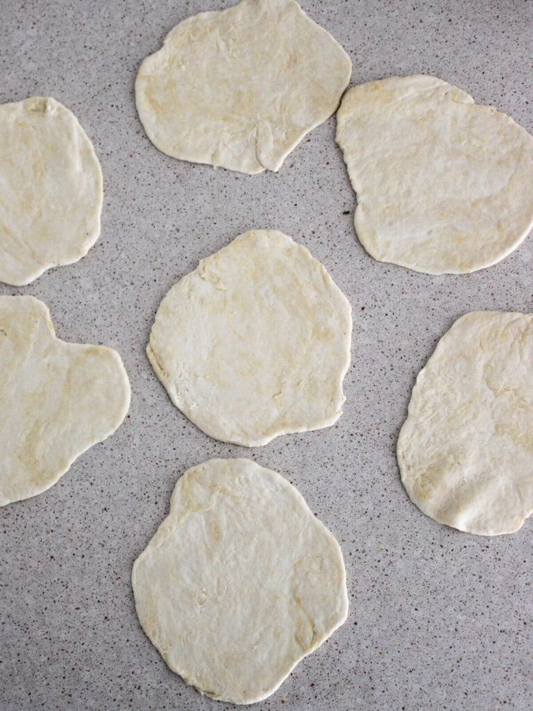rolling out the dough into circles on a countertop surface