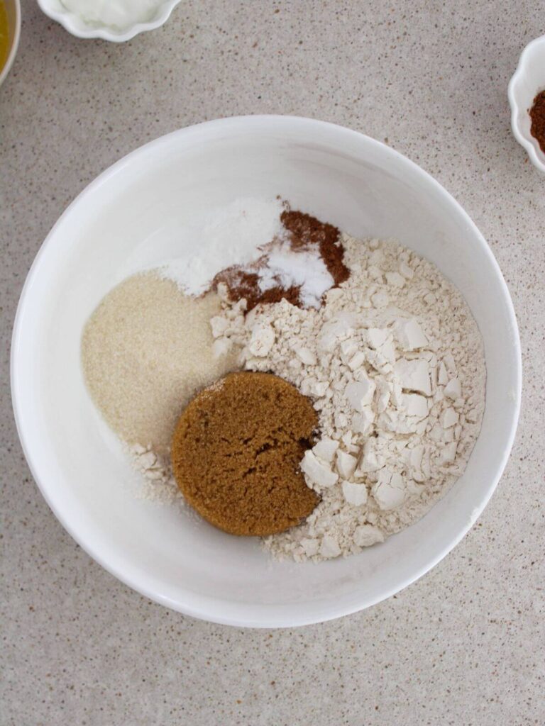 Mixing together the dry ingredients in a white bowl with a wooden spoon.