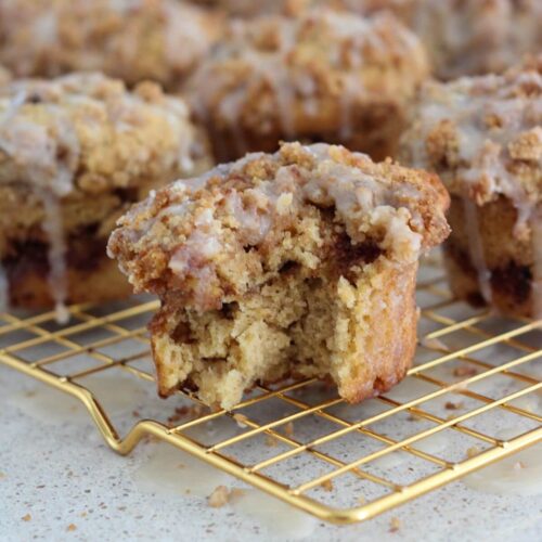 easy coffee cake muffins with a bite taken out of one on a golden cooling rack