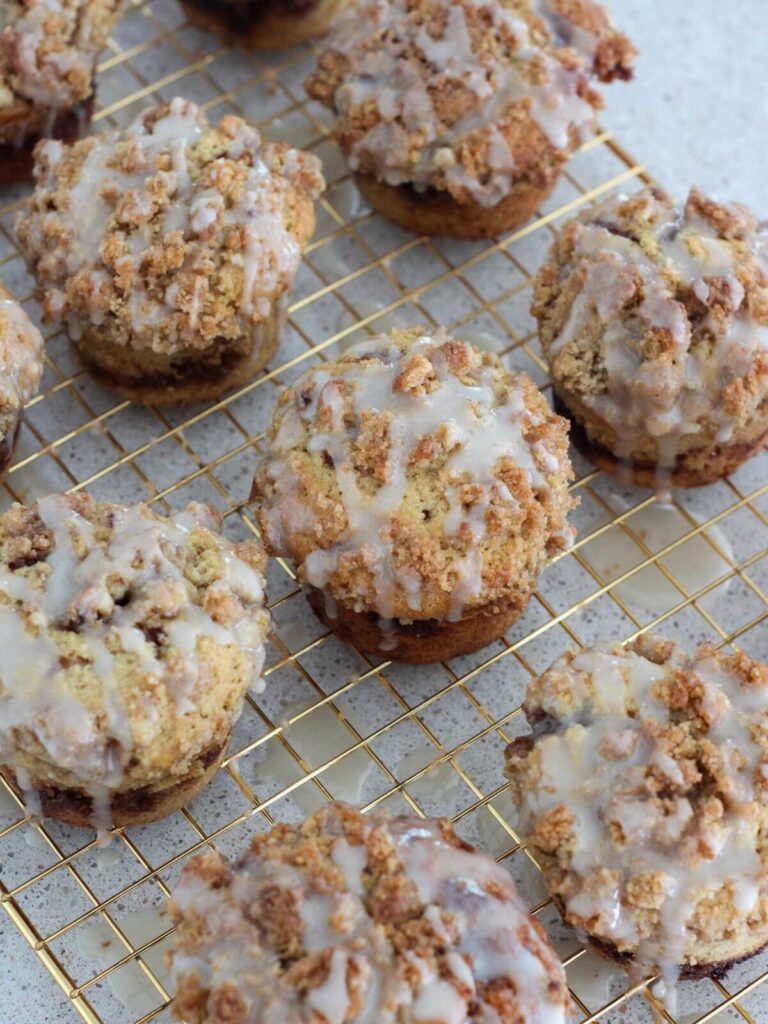 Muffins cooled on a golden cooling rack with glaze drizzled on top. 