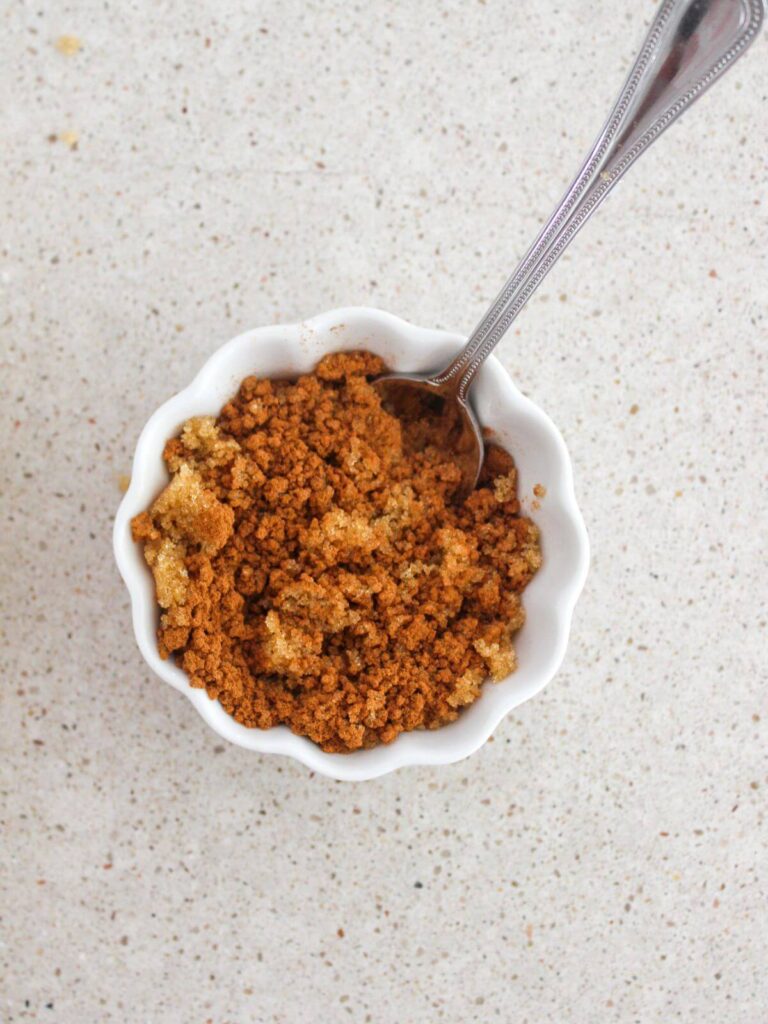 mixing the cinnamon and brown sugar in a white bowl with a silver spoon 