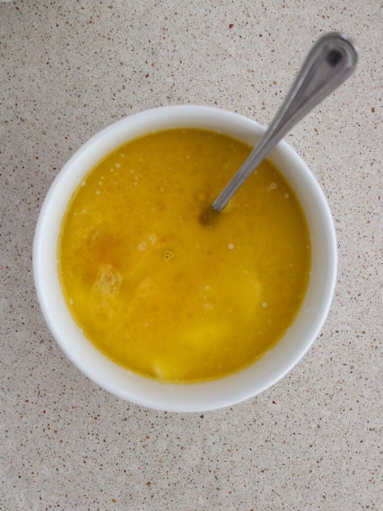Mixing the wet ingredients together in a white bowl with a silver spoon