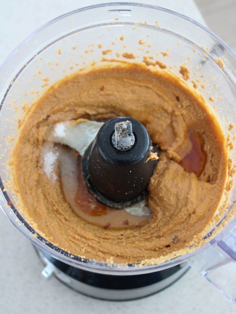 adding honey, salt and oil to the peanut mixture in the food processor