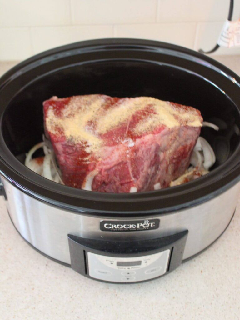 Adding the seasonings to the roast inside the crockpot