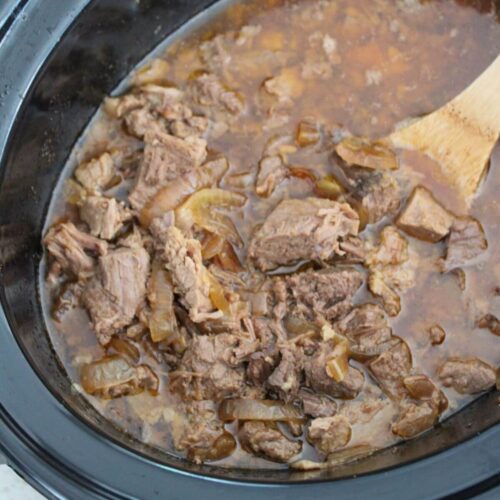 simple crockpot roast beef in a crockpot ready to eat with a wooden spoon