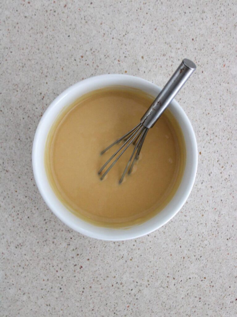 ingredients in a white bowl mixed together with a stainless steel whisk