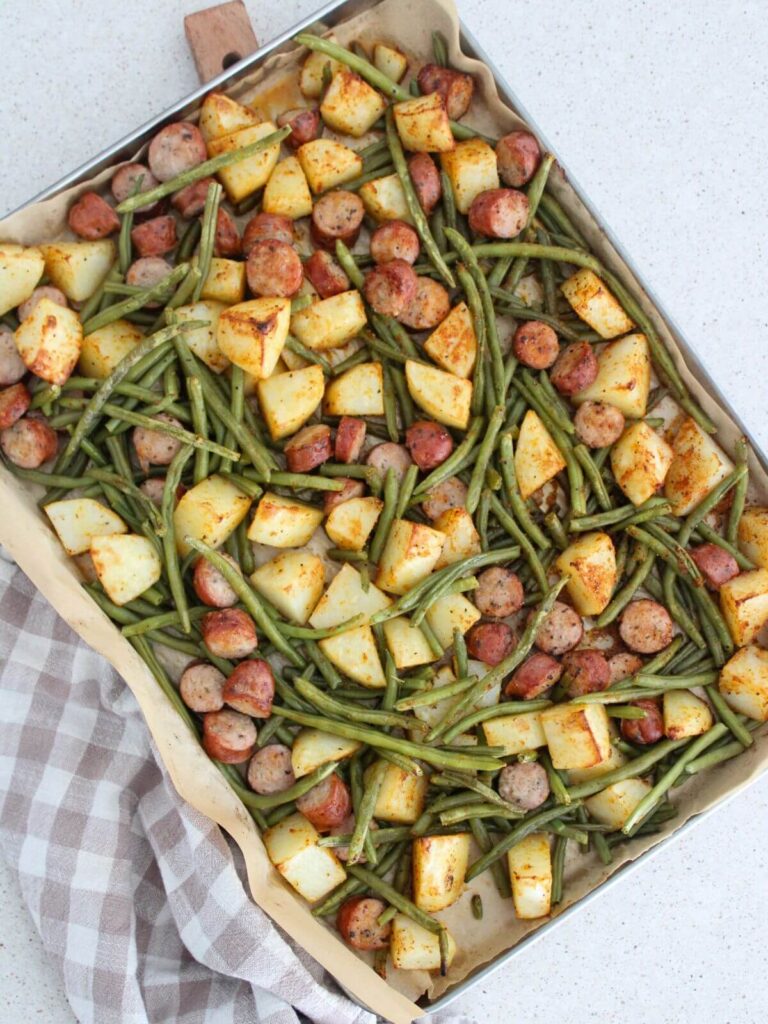 Sheet Pan Chicken and Sausage ready to eat on a sheet pan with parchment paper and a plaid napkin