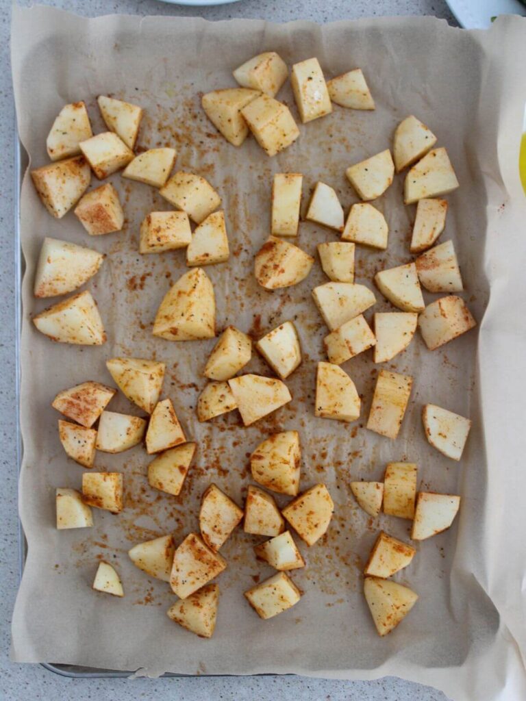 potatoes cut and ready to roast on a sheet pan with parchment paper
