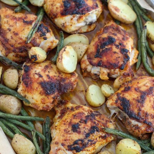 Sheet Pan Lemon Chicken Thighs with green beans and baby potatoes on a sheet pan with parchment paper