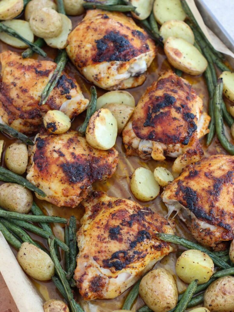 Sheet Pan Lemon Chicken Thighs with green beans and baby potatoes on a sheet pan with parchment paper