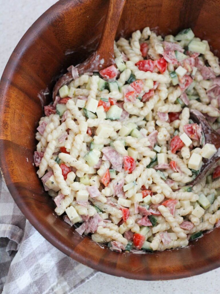 Creamy Italian Pasta Salad in a wooden bowl with a wooden spoon with a plaid napkin next to it