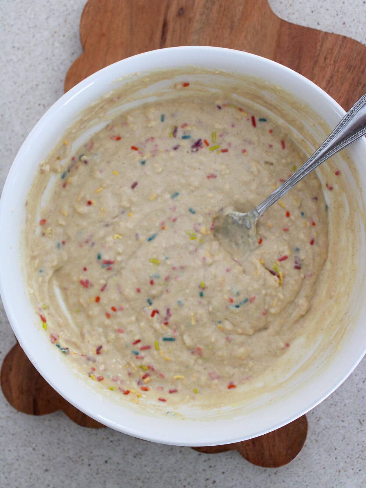 the sprinkles all added and stirred in with a silver spoon in a white bowl