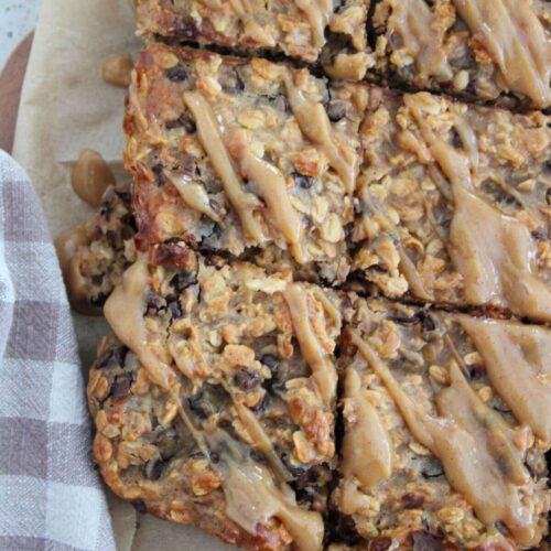 bars cut into squares on parchment paper on a cutting board with a plaid napkin next to it.