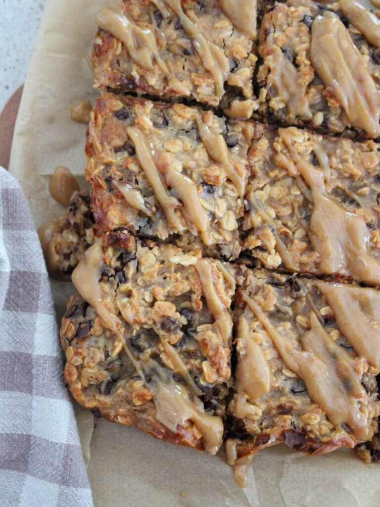 bars cut into squares on parchment paper on a cutting board with a plaid napkin next to it.