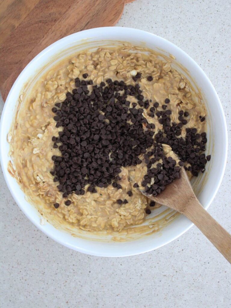 Adding the chocolate chips into the batter in the with bowl with a wooden spoon