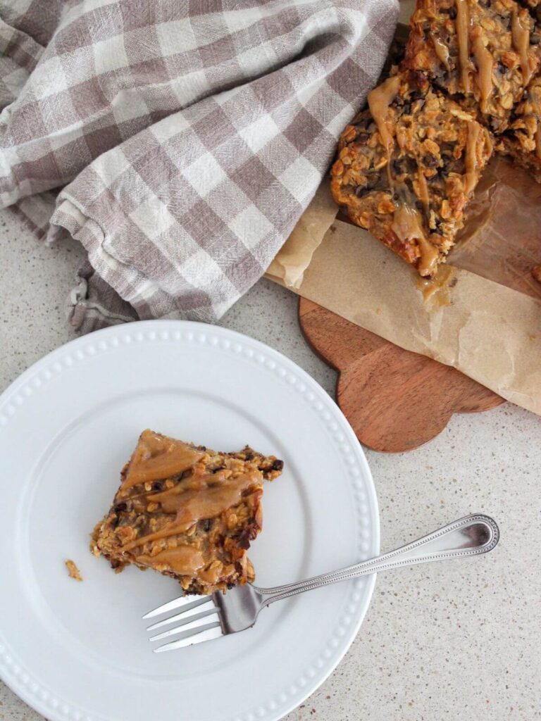 Peanut Butter Oatmeal Bars on a cutting board and a white plate with a fork and a plaid napkin next to it